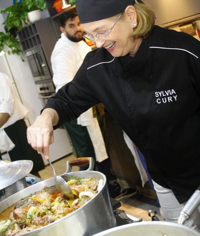Sylvia Cury servindo, na cozinha do Cook's House